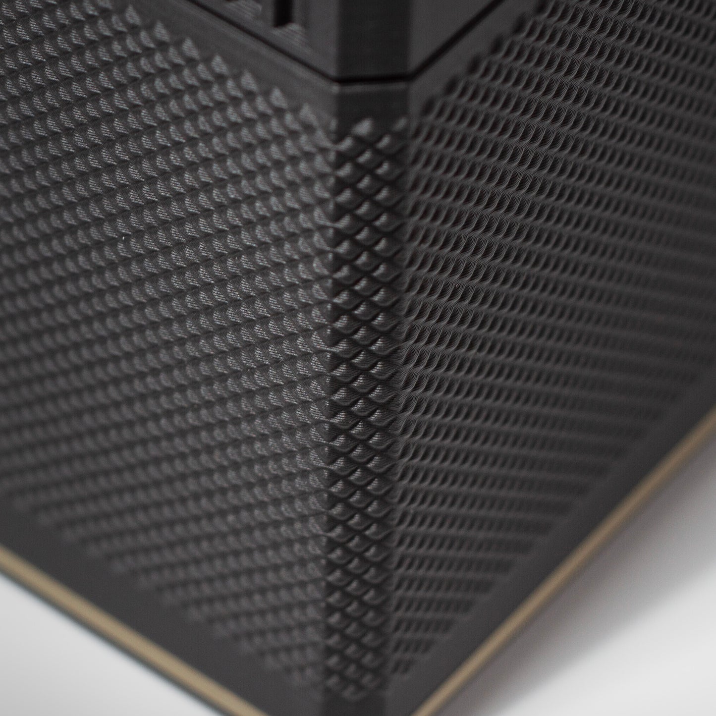 Close-up of the textured grip on the Iridium MTG Commander deck box with gold accent